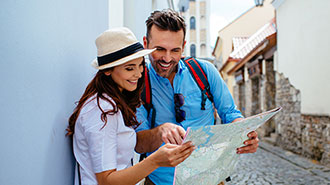 Frau und Mann im Reiseoutfit mit Landkarte in der Hand